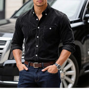A man wearing a black long-sleeve button-down shirt with white buttons, 