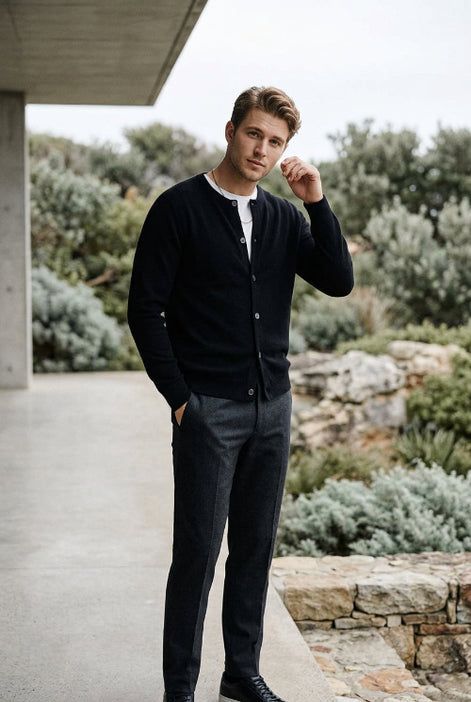 A black long-sleeve knit cardigan sweater hanging on a dark wooden hanger against a dark gray background.
