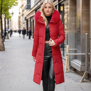 Woman wearing a red puffer coat with a fur collar on a city street.