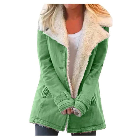 Woman wearing a green coat with wide cream fleece-look lapels, front pockets and cuff tabs over a white top and dark trousers