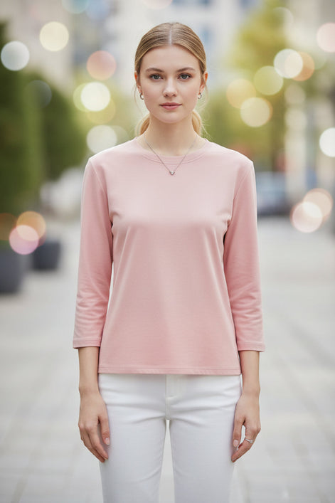 Person wearing a pink long-sleeve top with a neutral background