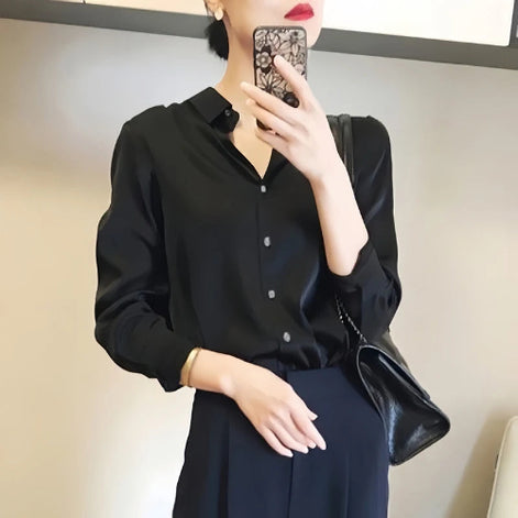 Black satin blouse worn by a model taking a mirror selfie.