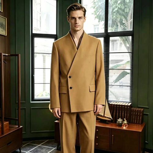 A man wearing a camel-colored double-breasted suit with a shawl collar, standing in a dark green room with large windows and wooden furniture.