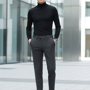 A person wearing dark gray textured slim-fit trousers, paired with a black long-sleeve top and black loafers, 