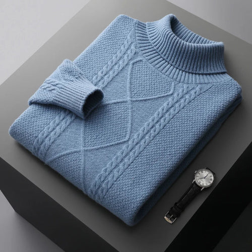 Folded blue sweater on a dark surface with a watch beside it