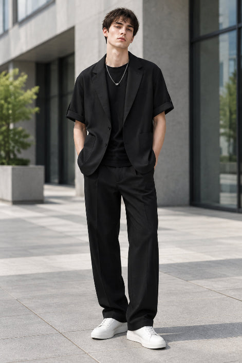 A black short-sleeve blazer styled over a black t-shirt with a silver necklace, shown against a plain white background.