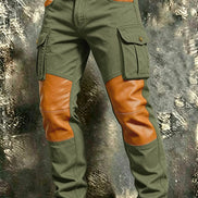 Olive green cargo pants with tan contrast panels at the knees and front pockets, flap thigh pockets, and a brown belt against a textured gray background.