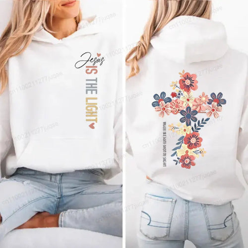 A white pullover hoodie shown on a model from the front and back. The front features the text 'Jesus IS THE LIGHT' in black, gray, and gold.