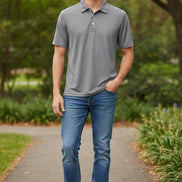 Man wearing a gray polo shirt and light blue jeans on a white background