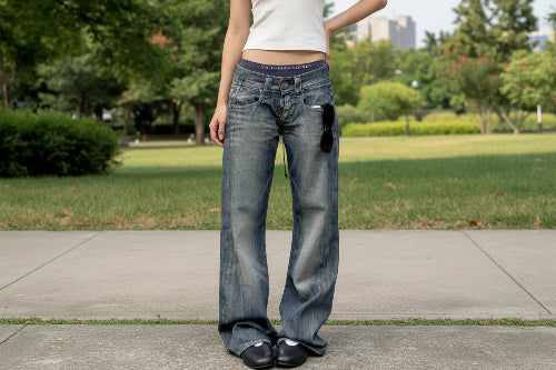 Person wearing blue jeans and a white top with a visible brand logo, standing on a street.