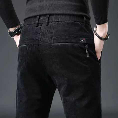 Black corduroy pants worn by a person on a gray background