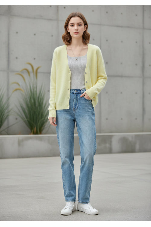 A woman wearing a soft pastel yellow cardigan sweater over a light gray top and blue jeans, 