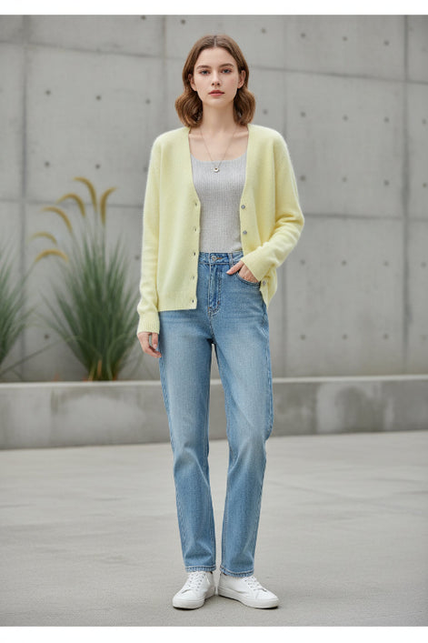 A woman wearing a soft pastel yellow cardigan sweater over a light gray top and blue jeans, 