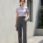 Purple satin blouse on a hanger against a neutral background