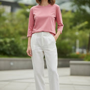 Person wearing a pink long-sleeve top in a softly lit room.