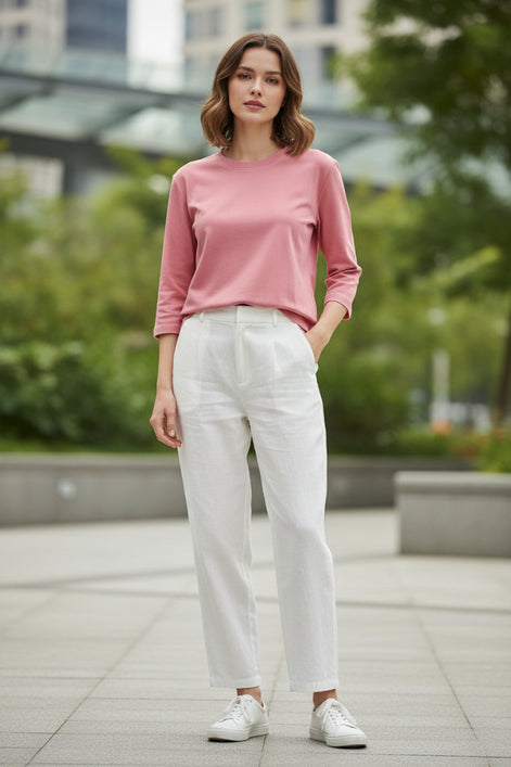 Person wearing a pink long-sleeve top in a softly lit room.