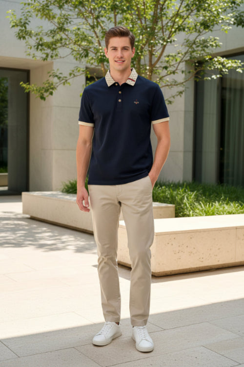 Navy blue polo shirt with patterned collar held by a hand, with more shirts in the background.