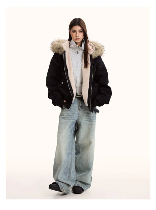 Person wearing a black coat with fur hood, light shirt, and blue jeans on a white background