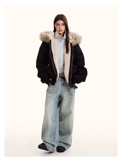 Full-length view of a model wearing a black hooded jacket with light fur-look trim and cream plush-look lining, paired with a gray zip-up top and wide-leg jeans