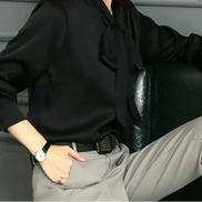 Woman wearing a black blouse and gray pants sitting on a chair.