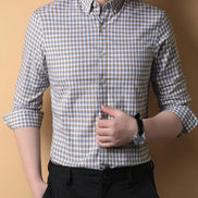 Person wearing a checkered shirt with rolled-up sleeves against a beige background
