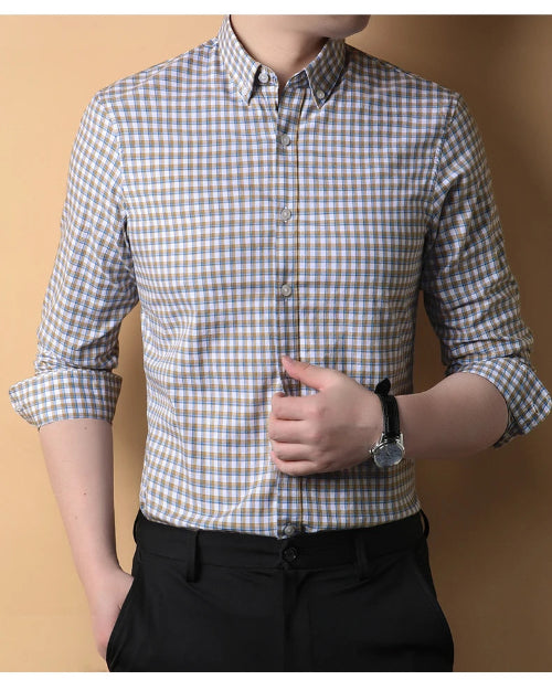 Person wearing a checkered shirt with rolled-up sleeves against a beige background