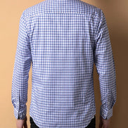 Blue and white checkered shirt worn by a person on a brown background