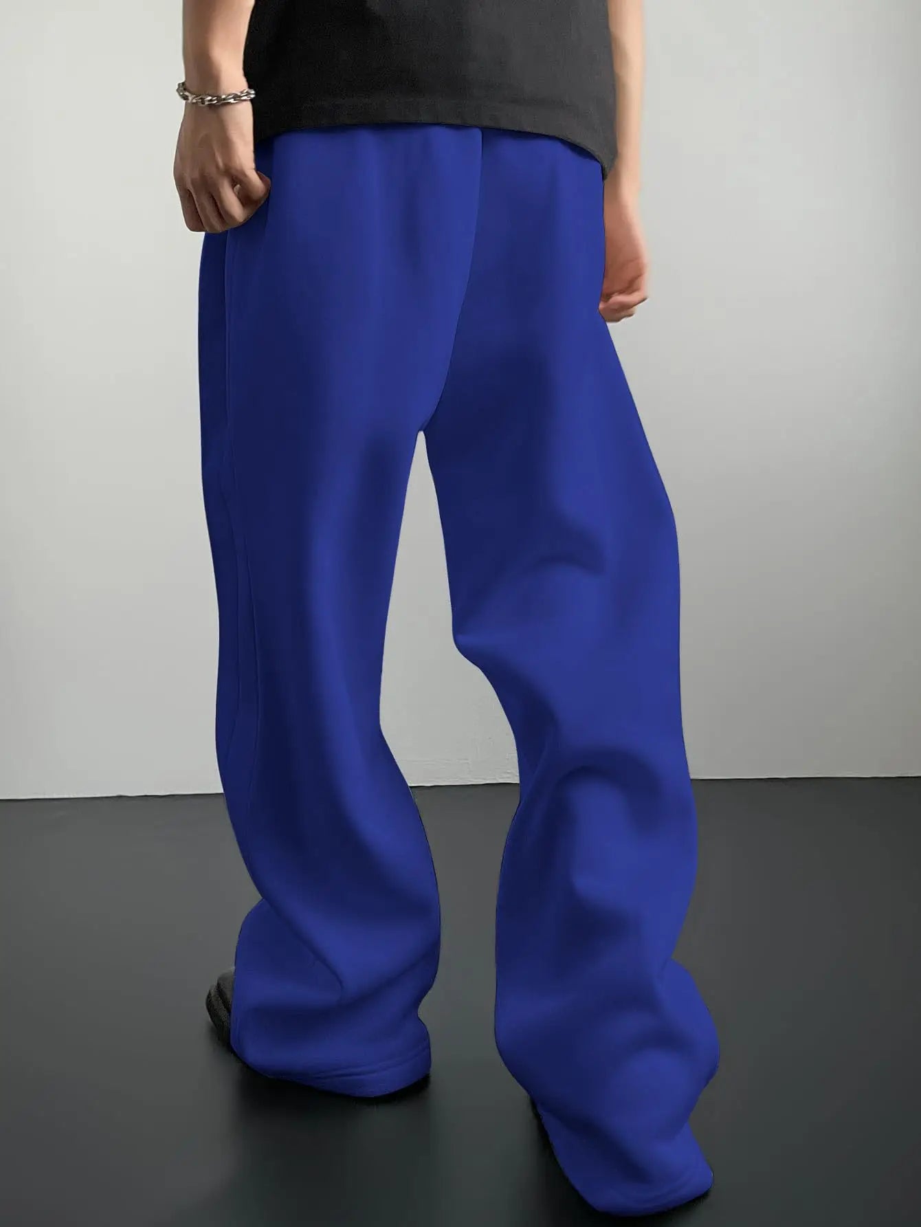 Person wearing blue pants and a black top against a gray background