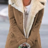 Woman outdoors wearing a tan coat with wide cream fleece-look lapels, front pockets and cuff tabs over a white top