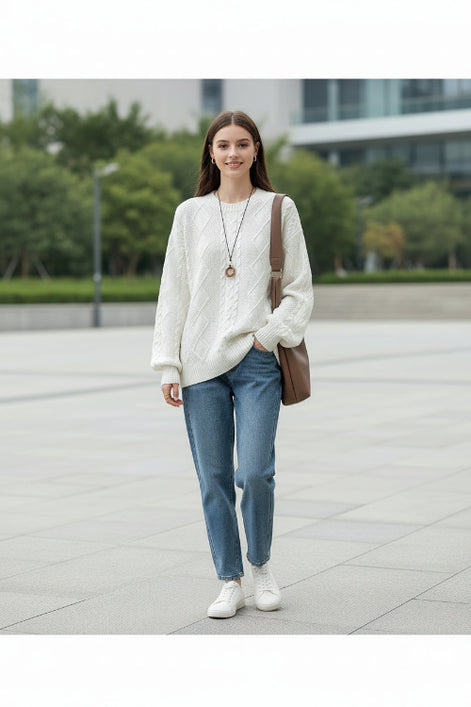 A woman wearing a cream-colored cable-knit sweater with textured diamond patterns, 