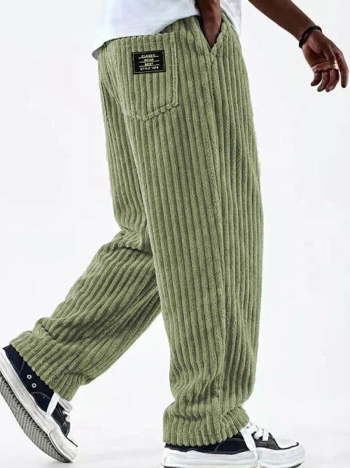 Green ribbed pants worn by a person on a white background