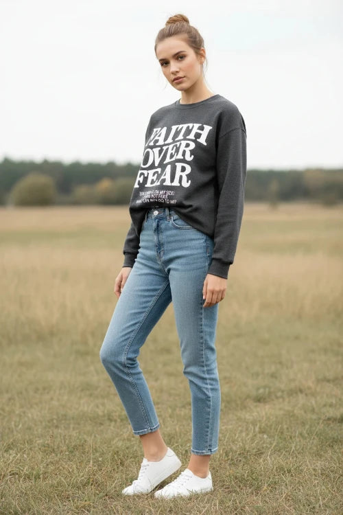 Dark gray sweatshirt with 'Faith Over Fear' text on a wooden background