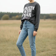 Dark gray sweatshirt with 'Faith Over Fear' text on a wooden background