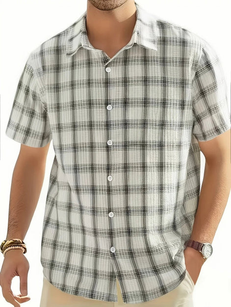 Man wearing a plaid shirt with a white collar on a plain background