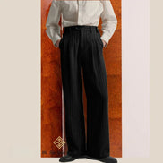 Person wearing a white shirt and black wide-leg pants against a wooden panel background