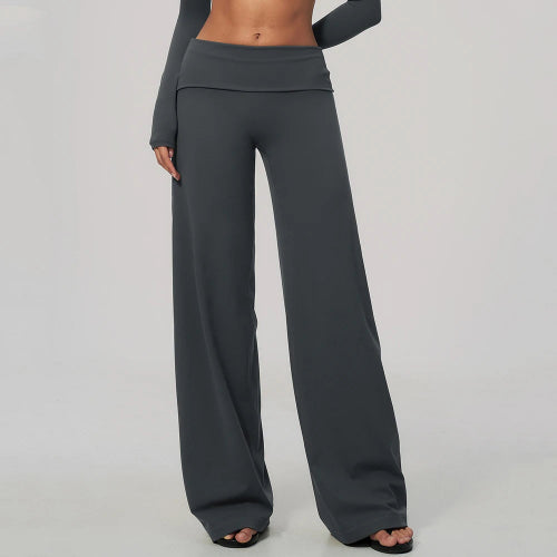 A model wearing dark gray wide-leg lounge pants with a high-waisted, double-layered waistband, paired with a matching long-sleeve top and black sandals,
