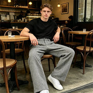 Gray herringbone wide-leg pants worn by a man at a cafe