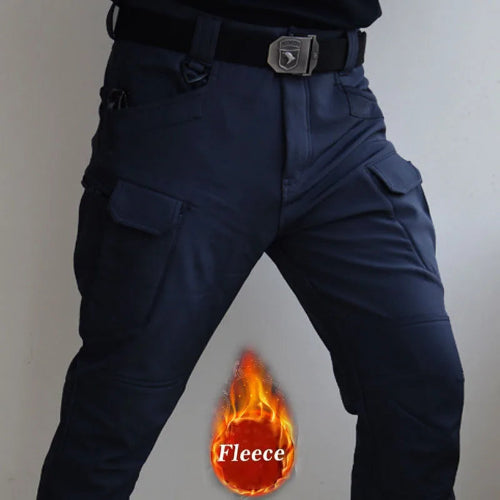 Front view of a model wearing navy blue cargo pants with flap thigh pockets and a black buckle belt, alongside a fleece label graphic against a light gray background.⠋