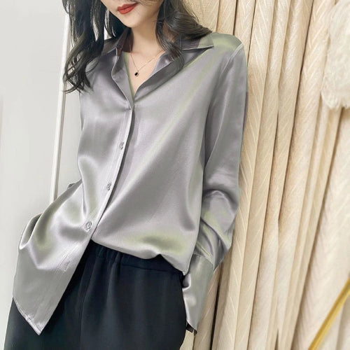 Person wearing a light gray satin shirt with a neutral background