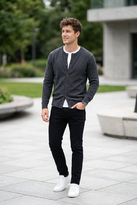 A dark gray knit cardigan sweater hanging on a wooden hanger against a dark gray background.