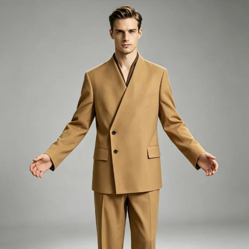 A man modeling a tan double-breasted suit with a unique wrap-style collar, standing against a neutral gray studio background.