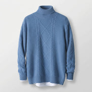 A dusty blue cable-knit mock neck sweater displayed on a wooden hanger against a white background.