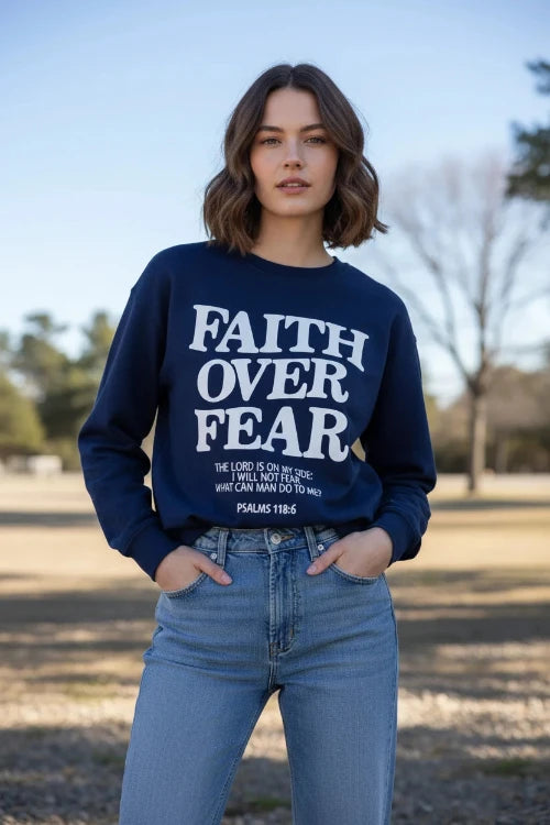 Navy sweatshirt with 'Faith Over Fear' text on a wooden background