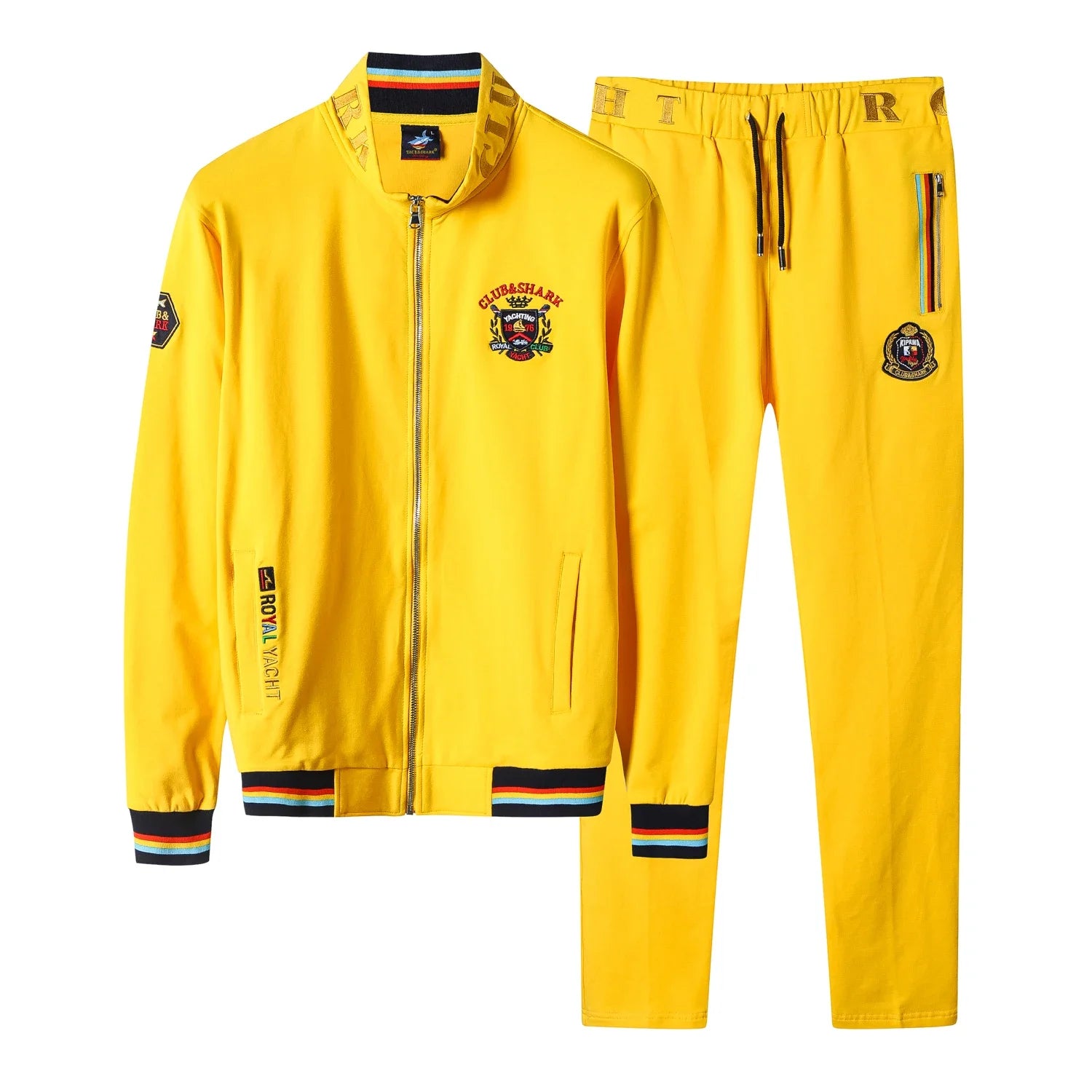 A bright yellow two-piece tracksuit set consisting of a zip-up jacket and matching pants, featuring multicolor striped ribbed cuffs and hems, a front zipper, and various embroidered patches.