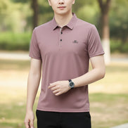 Person wearing a mauve polo shirt with a logo on a gray background