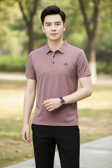 Person wearing a mauve polo shirt with a logo on a gray background
