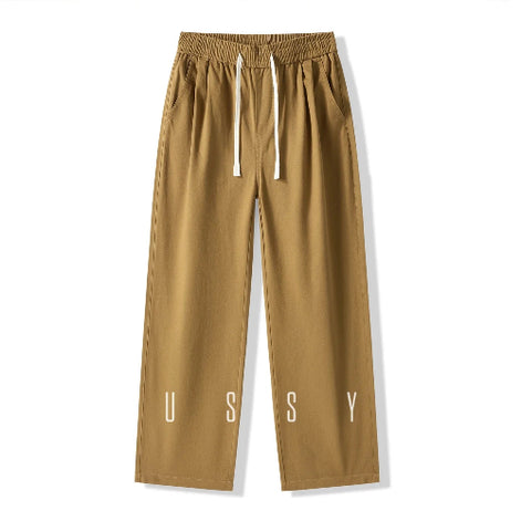 Front view of khaki loose-fit straight-leg pants laid flat, showing an elastic waistband, white drawstring, and slanted side pockets.