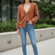 A fuzzy, soft-textured cardigan sweater in a warm rust or terracotta orange-brown color, worn over a beige ribbed top. 