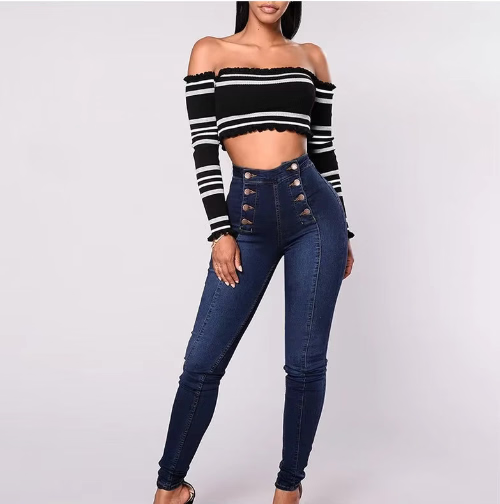 Woman wearing a black and white striped off-shoulder top and blue jeans on a light gray background