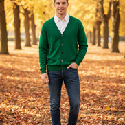 Green cardigan over a white shirt on a wooden hanger against a dark background